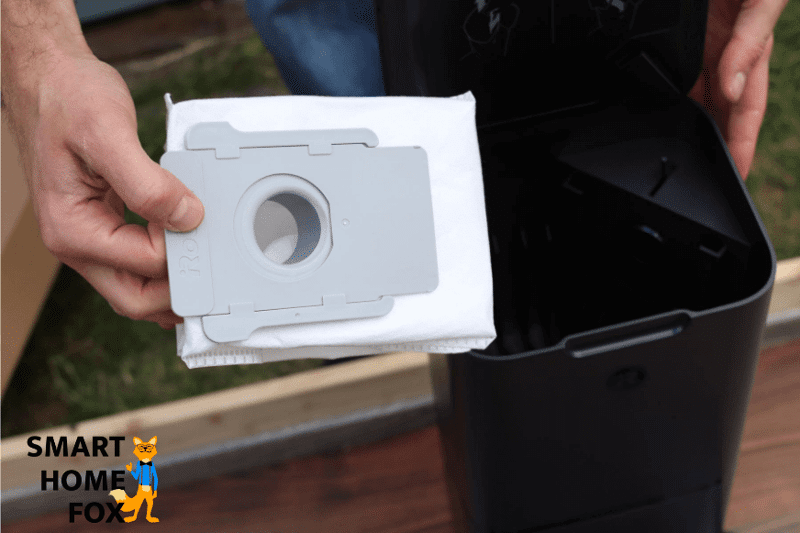 Inserting a disposable dust bag into the auto-empty dustbin.